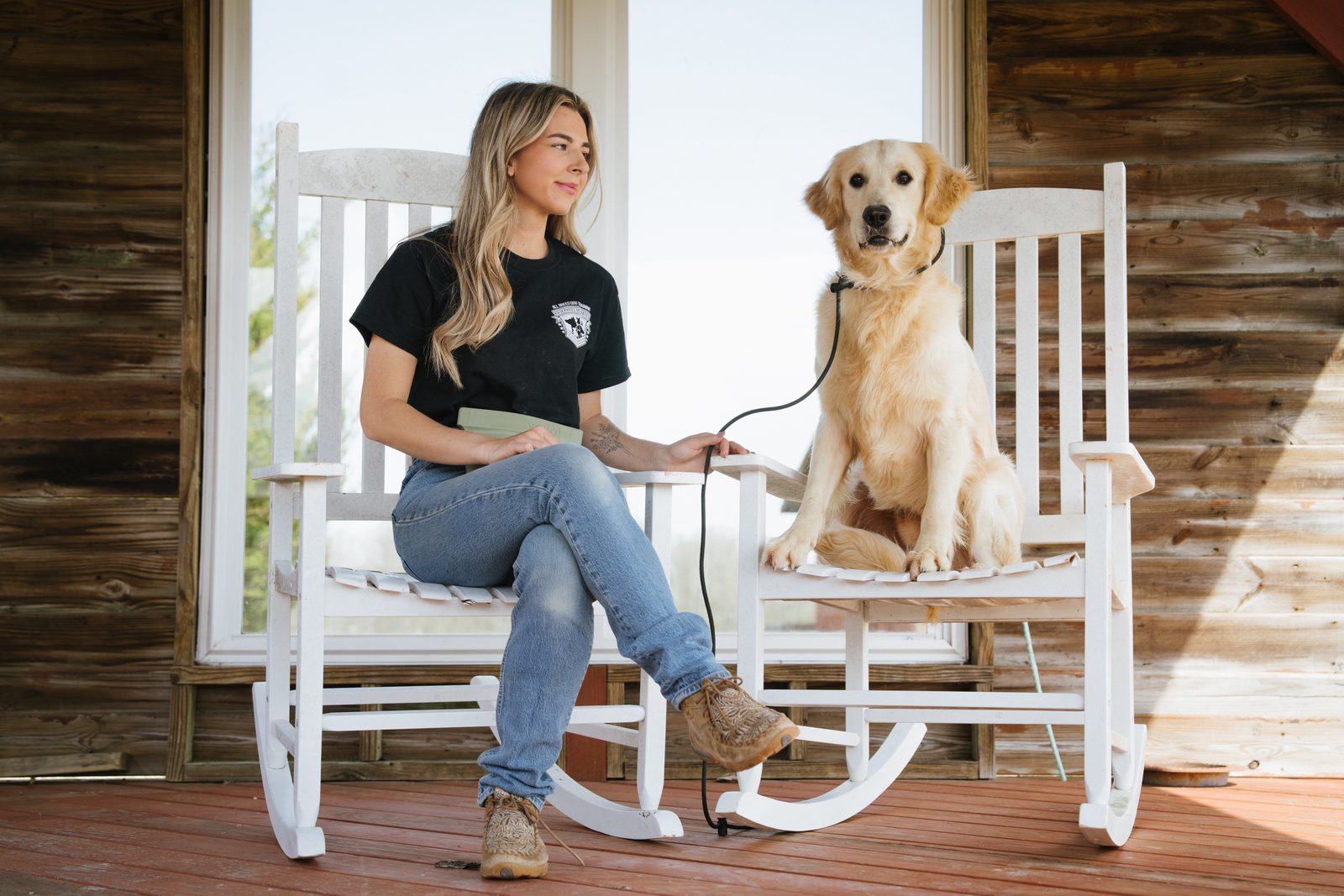 A woman and a golden retriever relaxing in rocking chairs on a porch